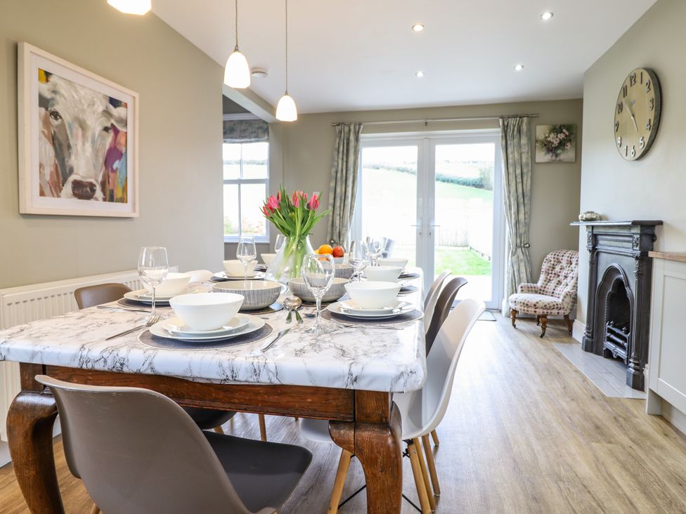 A dining room with a set table on a wooden table and a fireplace at Red House Farm in Llanfair Caereinion near Welshpool