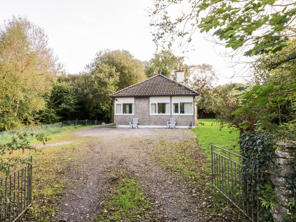 A small house with two chairs in front surrounded by trees at Lakeside in Cahir near Ballinrobe County Mayo