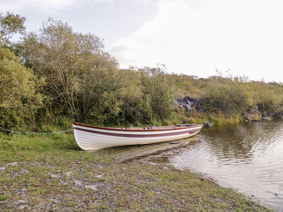 A small wooden boat tied to the shore on a lake with trees and rocks in the background at Lakeside in Cahir near Ballinrobe County Mayo