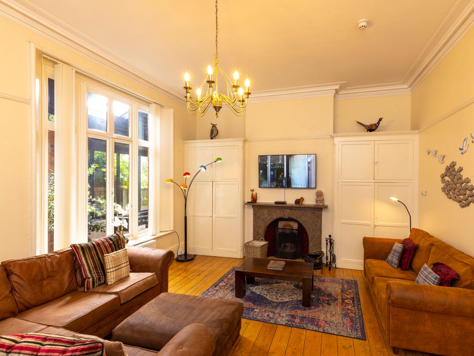 A living room with two brown sofas a wooden coffee table a fireplace and a large window at Roa Island House in Roa Island