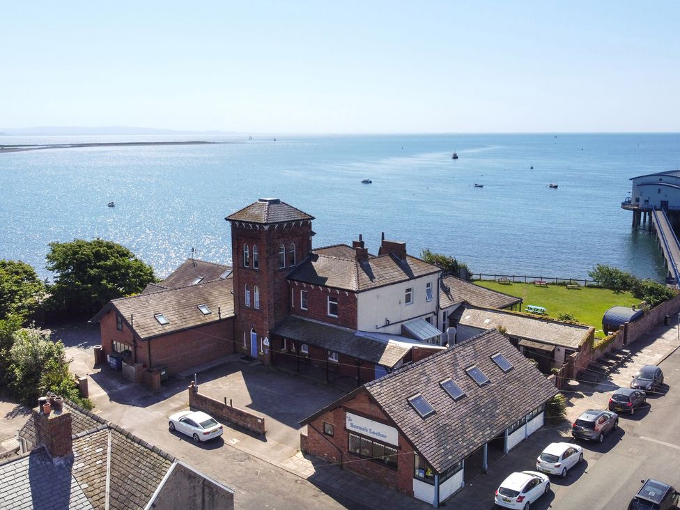 A waterfront property with multiple buildings and parked cars near a pier at Roa Island House in Roa Island