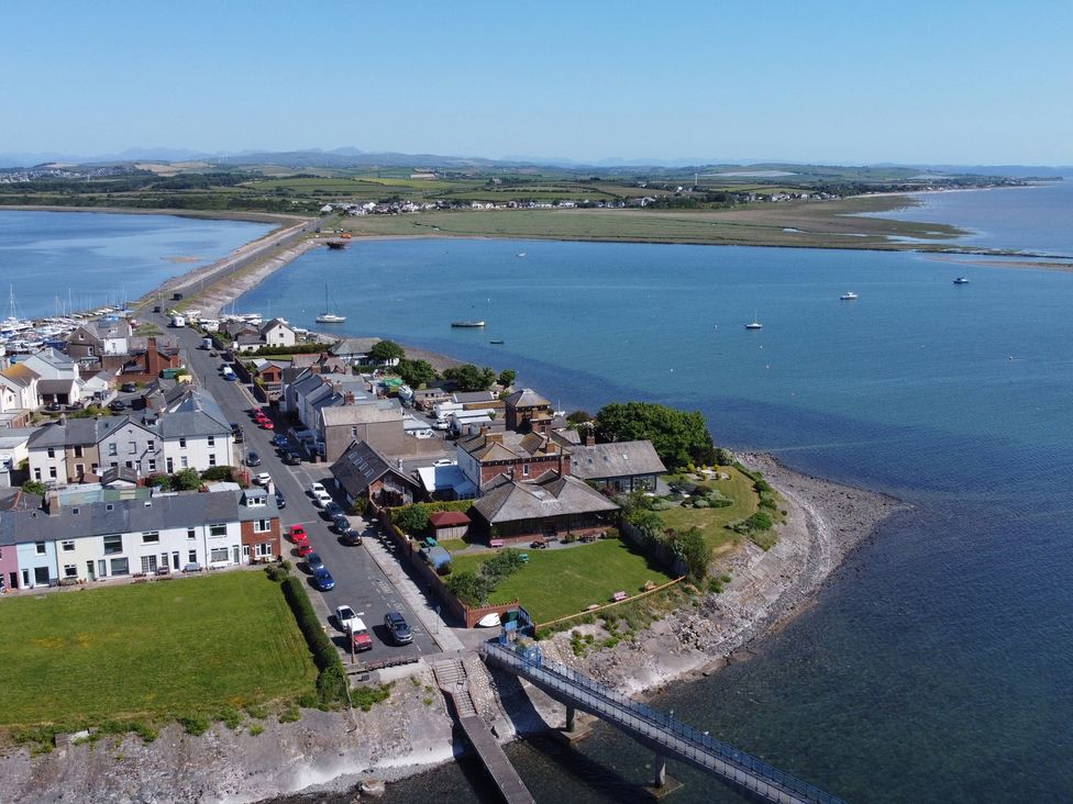A coastal village with houses near a pier and a road leading to a narrow strip of land over water at Roa Island House in Roa Island