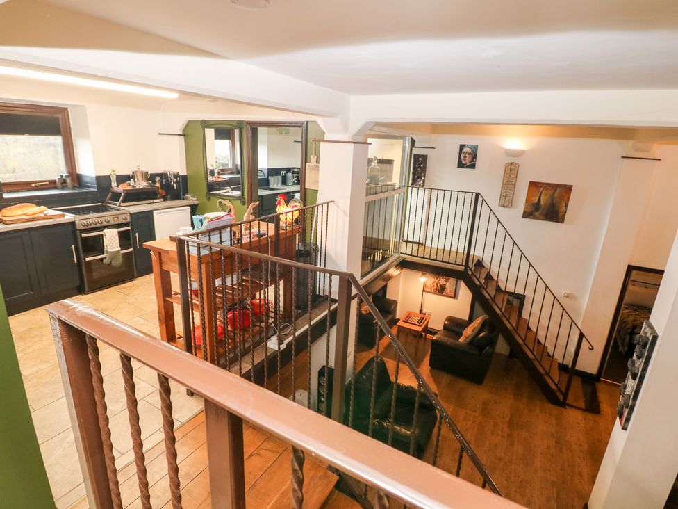 A kitchen with stove and counter next to a staircase leading down to a living area with chairs and a table at Cambridge Lodge in Wensley near Matlock