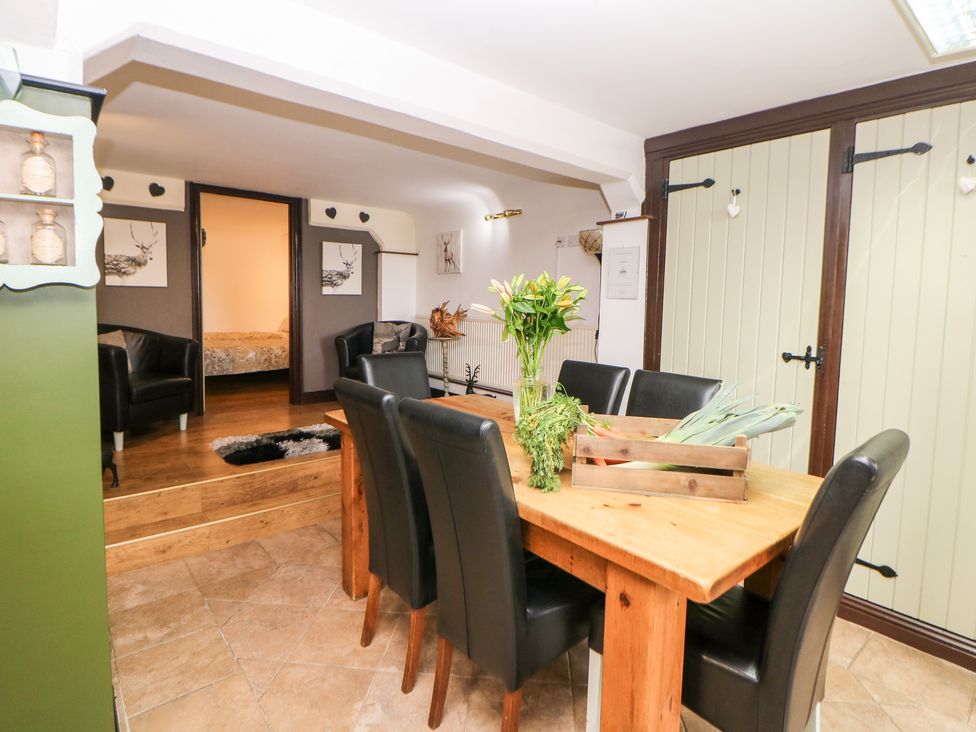 A dining room with a wooden table and black chairs with flowers in a vase and vegetables on the table at Cambridge Lodge in Wensley near Matlock