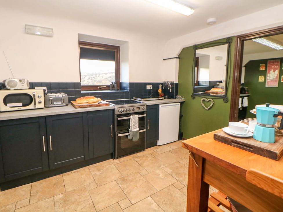 A kitchen with black cabinets a stove microwave toaster and bread on the counter at Cambridge Lodge in Wensley near Matlock