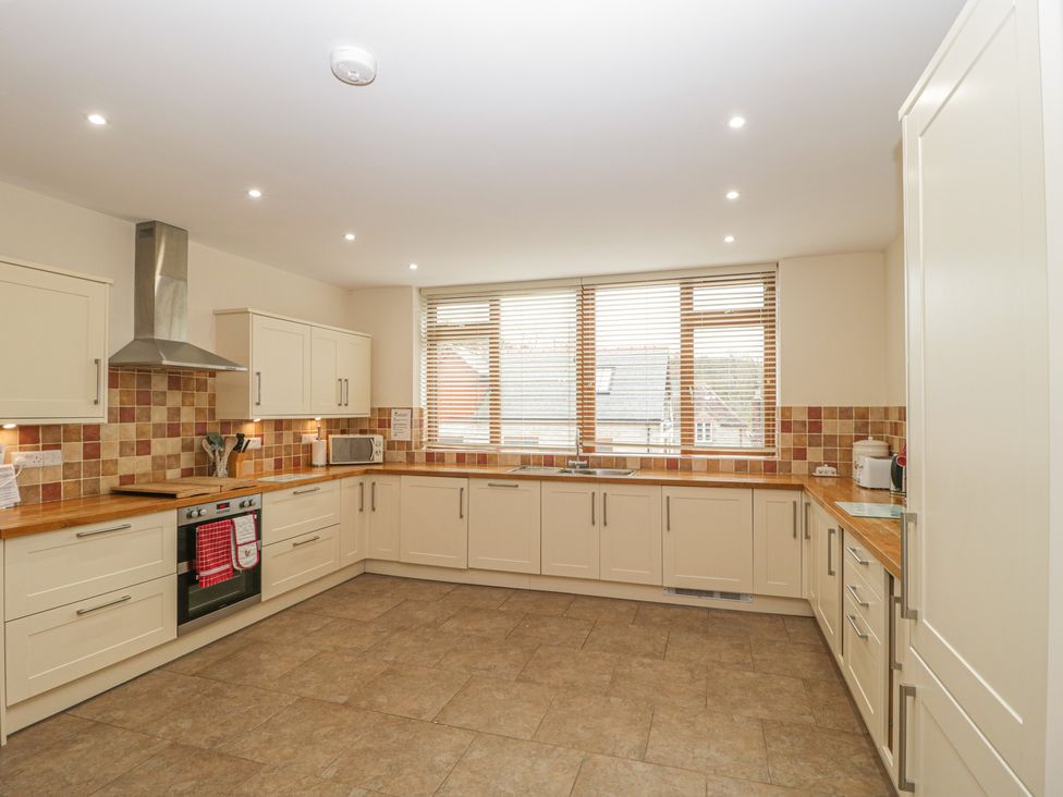 A kitchen with wooden countertops white cabinets a stainless steel oven and a large window at The Old Barn in Harman's Cross near Swanage