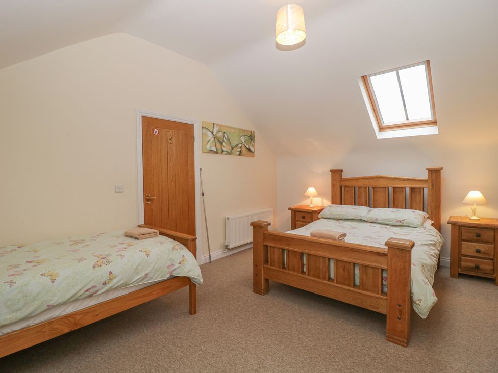 A bedroom with a double bed and a single bed with butterfly bedding at The Old Barn in Harman's Cross near Swanage