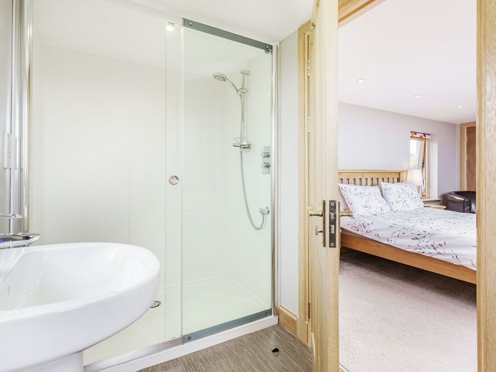 A bathroom with a shower and sink looking into a bedroom with a bed and window at Askival in Elgol