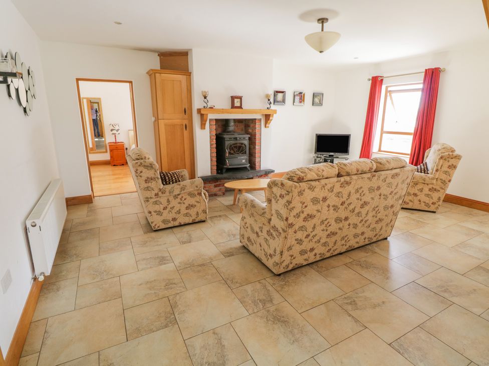 A living room with floral sofas a fireplace a television and red curtains at Blue Stack House Meenaguish Beg near Donegal Town County Donegal
