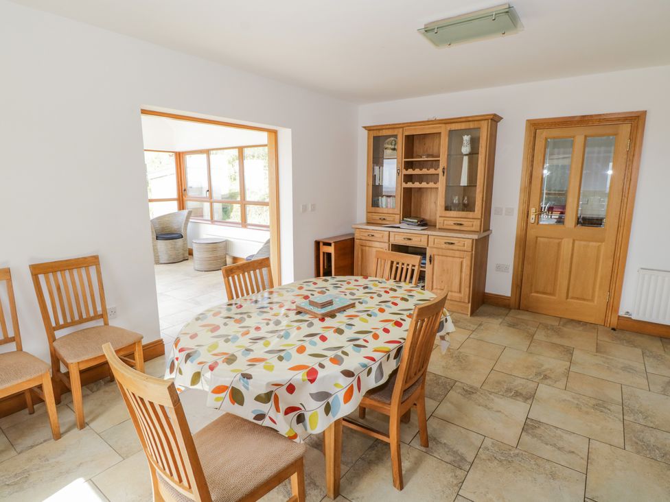 A dining room with a table covered by a patterned tablecloth surrounded by wooden chairs and a wooden cabinet at Blue Stack House in Meenaguish Beg near Donegal Town County Donegal