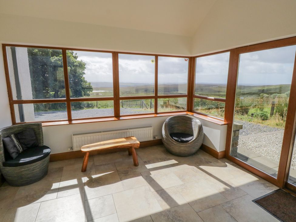A corner seating area with two round chairs and a wooden bench near large windows at Blue Stack House Meenaguish Beg near Donegal Town County Donegal