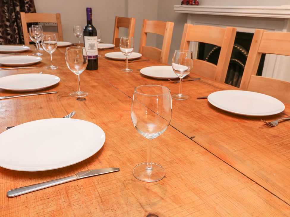 A dining table set with white plates wine glasses cutlery and a bottle of wine at Whitefriars Lodge in Settle