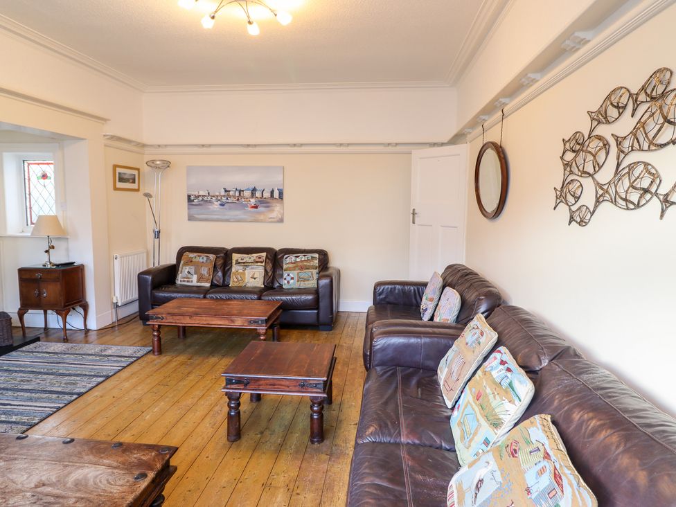 A living room with leather sofas wooden coffee tables and cushions at Meadway House in Rhos-on-Sea
