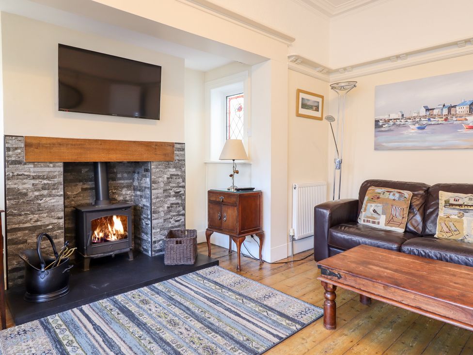 A living room with a fireplace television sofa wooden coffee table and side table at Meadway House in Rhos-on-Sea