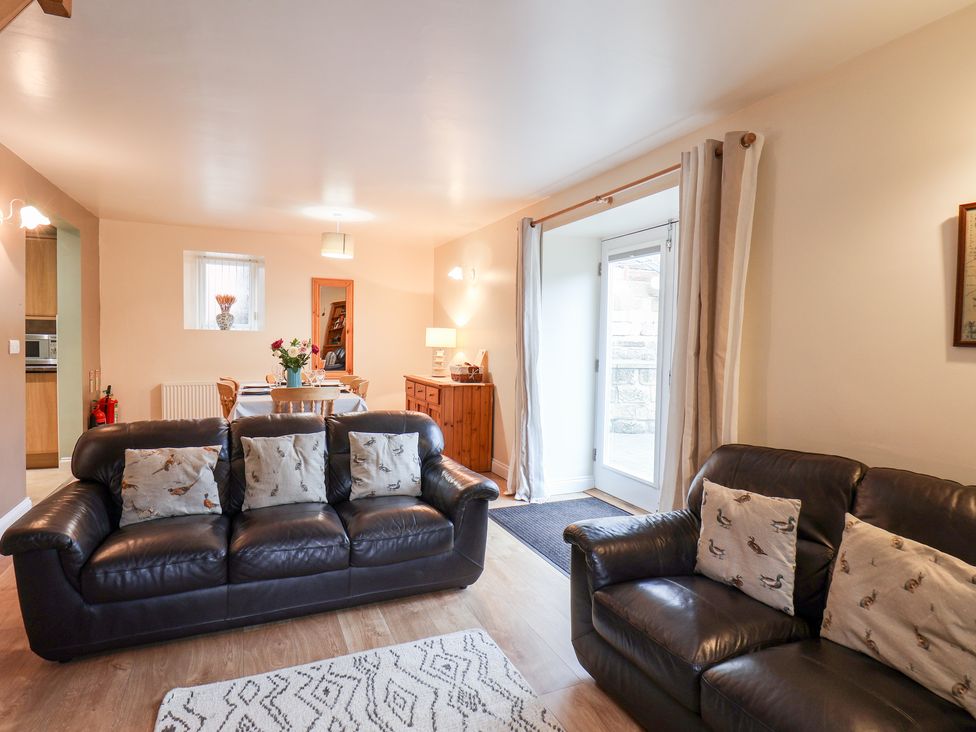 A living room with two leather sofas and a dining table in the background at Mulgrave Cottage in Dalehouse near Staithes