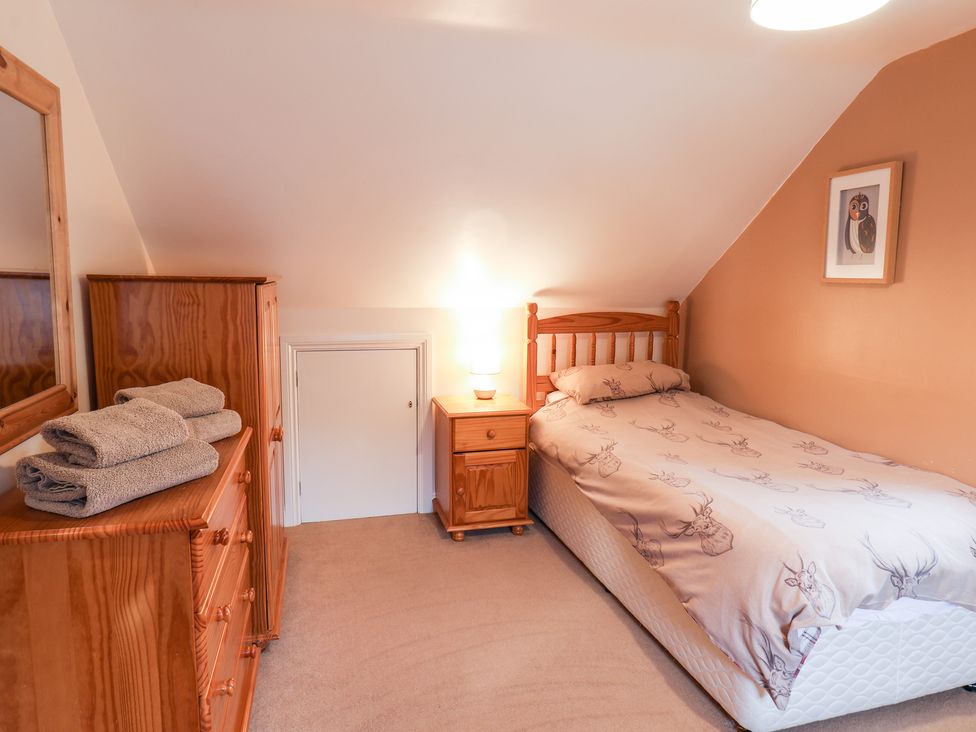 A bedroom with a single bed bedside table with lamp chest of drawers and wooden wardrobe at Mulgrave Cottage in Dalehouse near Staithes