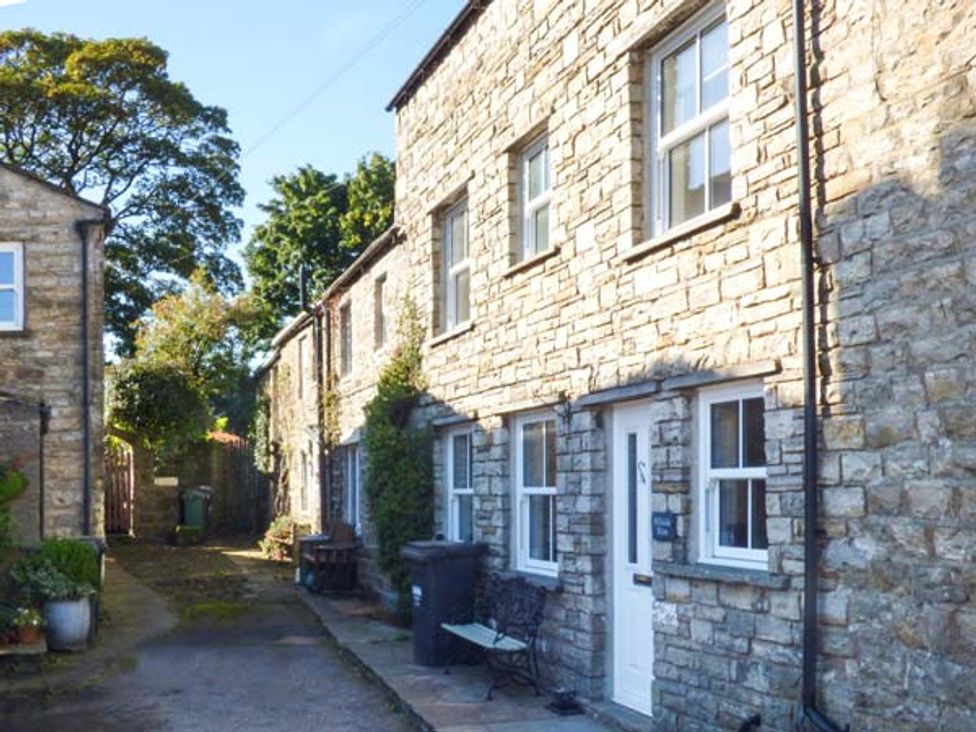 A stone terrace of houses with white doors and windows along a narrow paved pathway at Hillside View in Hawes