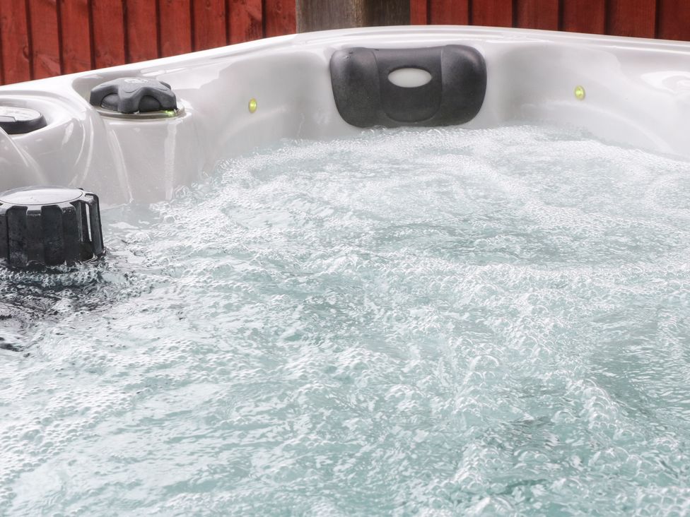 A bubbling outdoor hot tub with headrest and controls at Bryn Derw Holiday Cottage in Eglwysbach near Llanrwst and Conwy