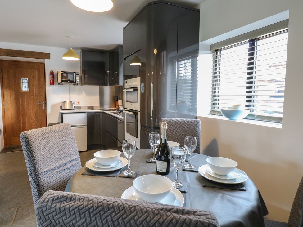 A dining table set with plates bowls wine glasses and a bottle in a kitchen at Tricker's Cottage in Morton on the Hill near Lenwade