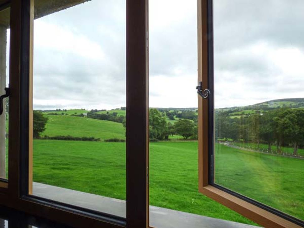 A view of green fields and trees through an open window at Tyn Y Celyn Uchaf Clocaenog near Ruthin