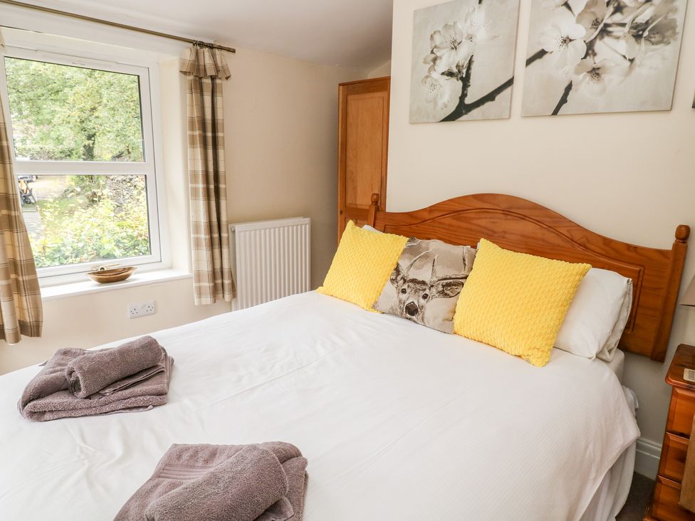 A bedroom with a wooden bed and yellow and animal print pillows at Fern House in Kettlewell