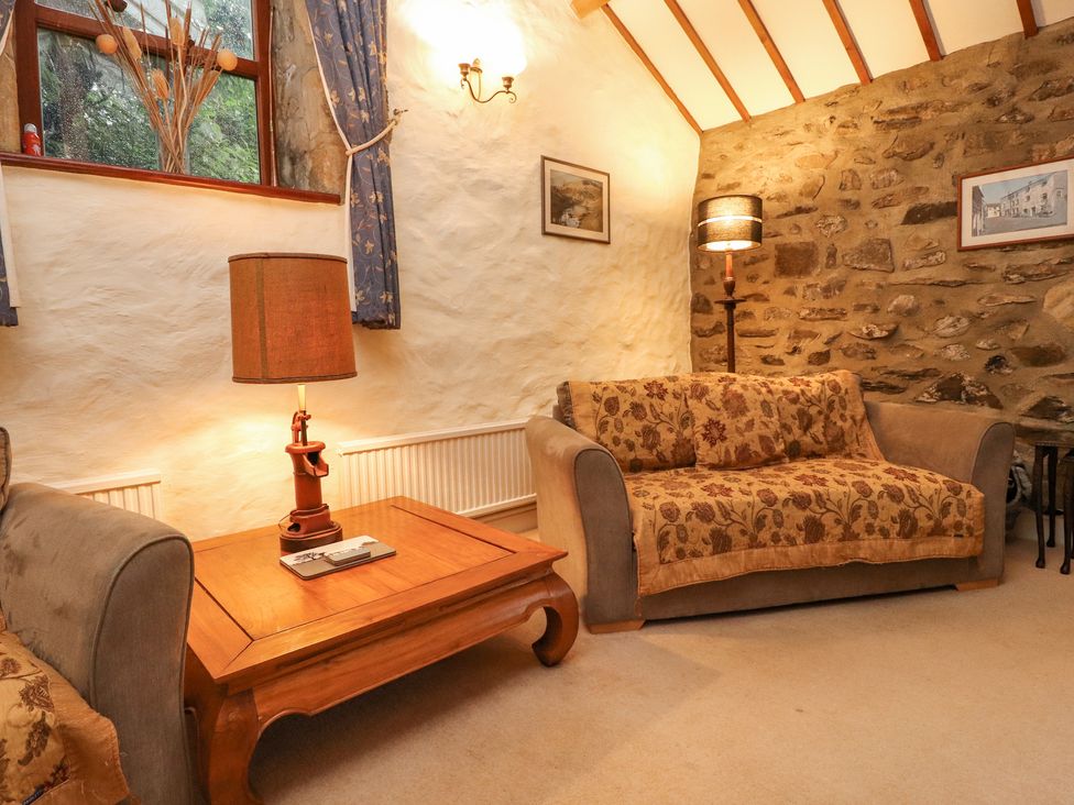 A living room with two sofas, a wooden coffee table with a lamp, stone and plaster walls at Haworth Barn in Stainforth near Settle