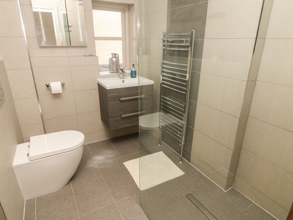 A bathroom with a toilet sink with vanity mirror towel rack and glass shower enclosure at Lonsdale Cottage in Kirkby Lonsdale