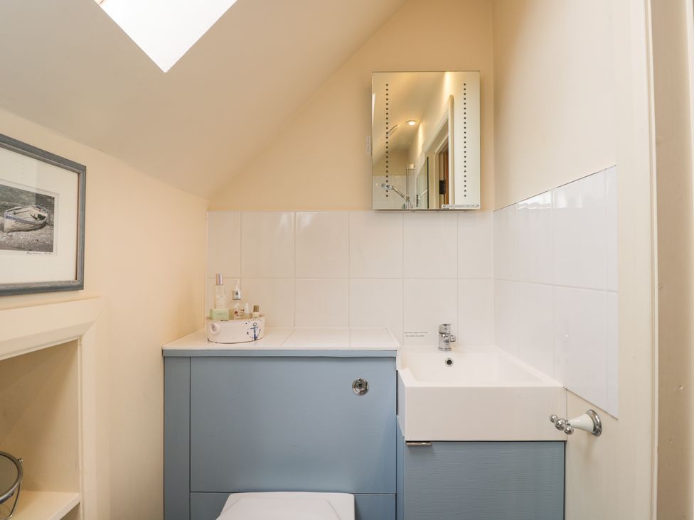 A small bathroom with a white sink and blue cabinet under a skylight at Shephard's Retreat in Charlton Mackrell near Somerton