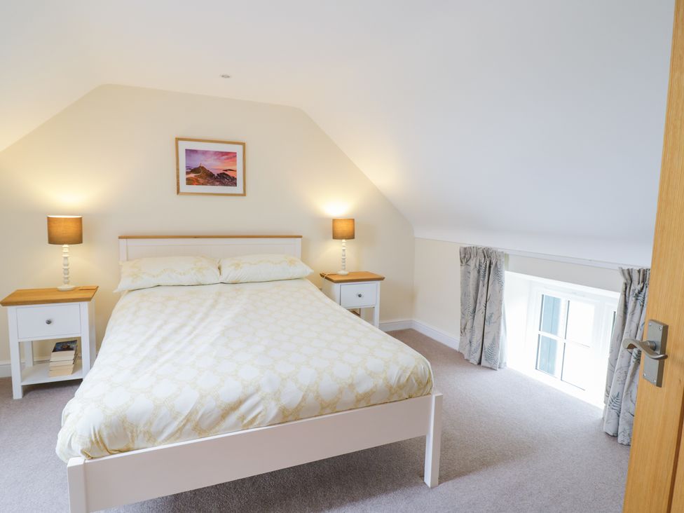 A bedroom with a bed bedside tables lamps and a window at Plas Tirion Cottage in Mostyn near Holywell