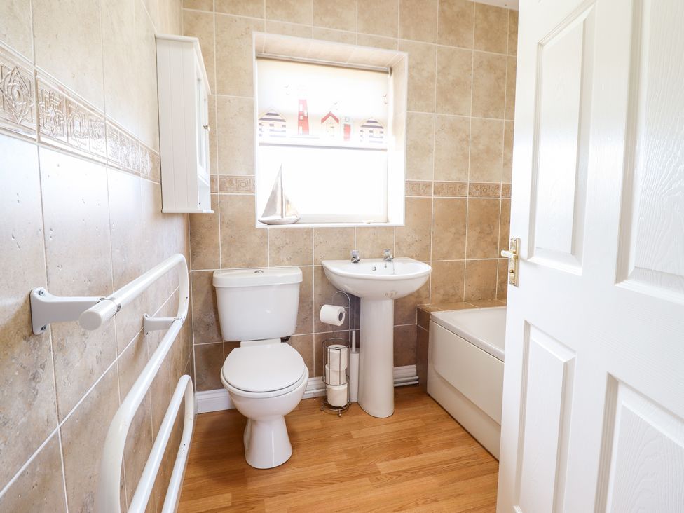 A bathroom with a toilet sink bathtub and a window at Sealyons Fairbourne near Dolgellau