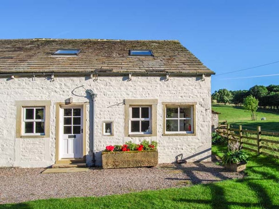 A white stone cottage with three windows a door and flower planters outside at The Nook Bank Newton in Bank Newton near Gargrave and Skipton