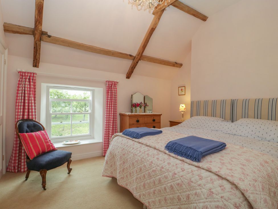 A bedroom with a double bed two blue blankets wooden dresser and a chair by a window at Drover's in Sutton Mallet