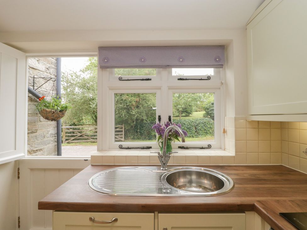 A kitchen sink with a faucet and flowers in a vase under the window at Drover's in Sutton Mallet
