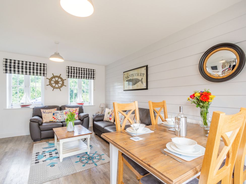 A living room with two leather sofas a coffee table and a dining table set with dishes at Lilipad Cottage The Bay near Filey