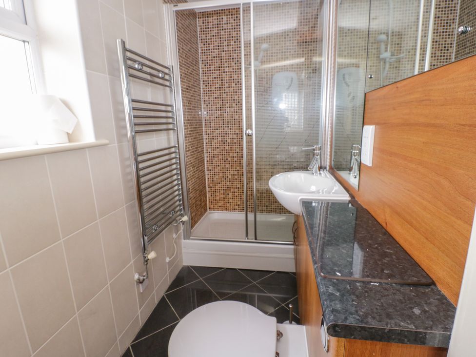 A bathroom with a shower cubicle a sink a toilet and a heated towel rail at Llecyn Braf in Amlwch