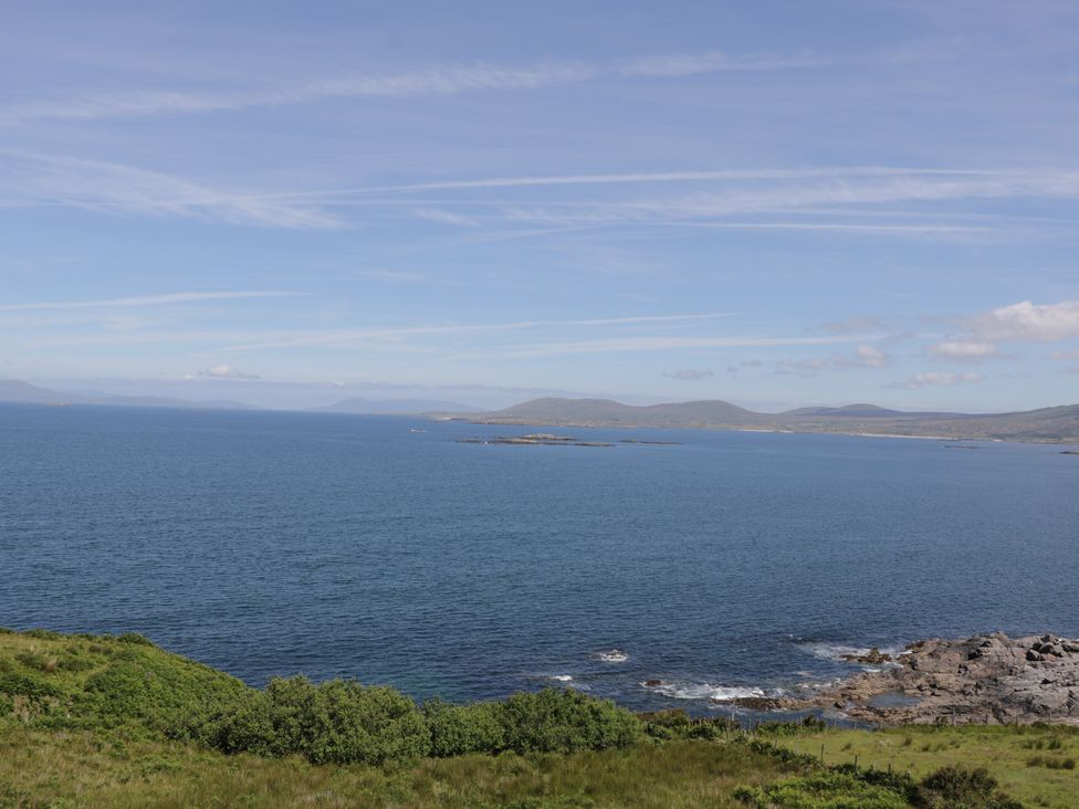 A coastal landscape with ocean water rocky shoreline and distant hills at Seaspray in Tully County Galway