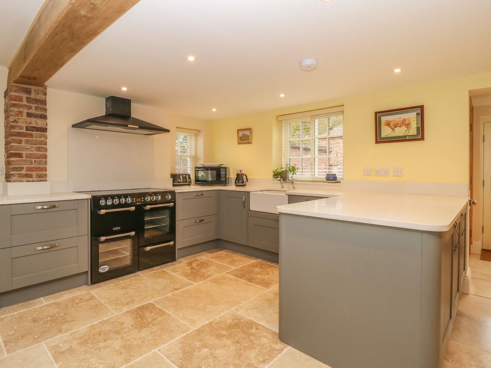 A kitchen with grey cabinets black oven and stove white countertops and tiled floor at Copmanthorpe Hall in Copmanthorpe