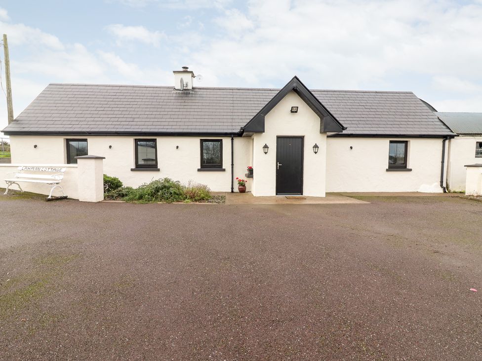 Exterior view of a single-story white cottage with black framed windows and door at Laharn Cottage in Killorglin County Kerry