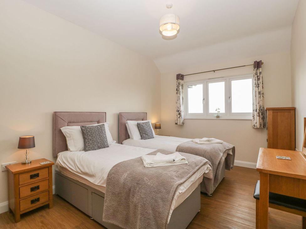 A bedroom with two single beds bedside tables with lamps a wooden desk and a window with curtains at Rectory Farm View Queen Camel near Yeovil
