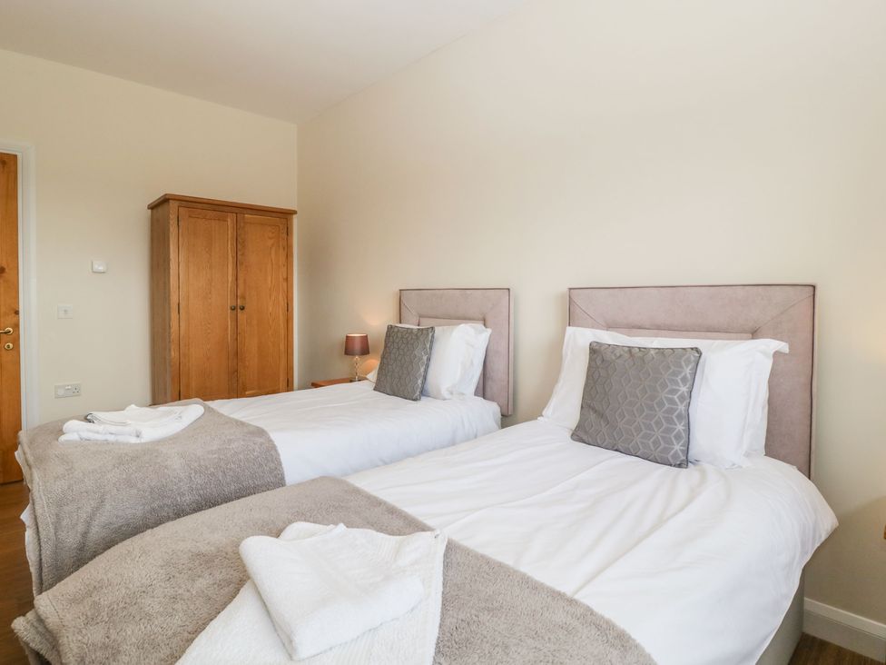 A bedroom with two single beds gray pillows wooden wardrobe and bedside lamp at Rectory Farm View Queen Camel near Yeovil