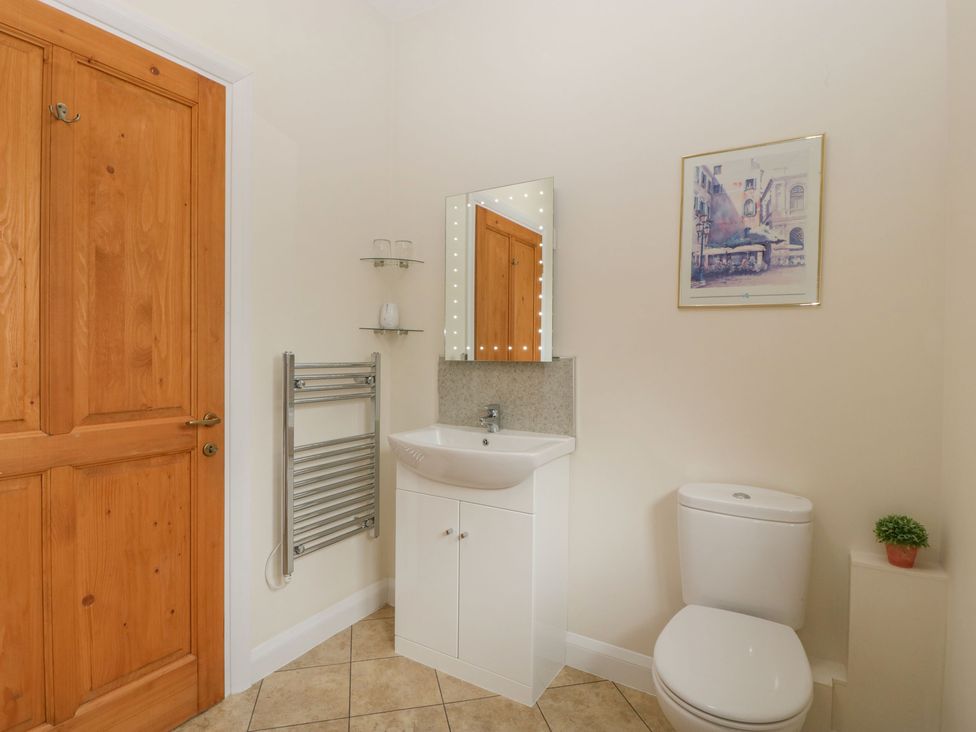 A bathroom with a wooden door white sink with cabinet mirror towel rack and toilet at Rectory Farm View Queen Camel near Yeovil