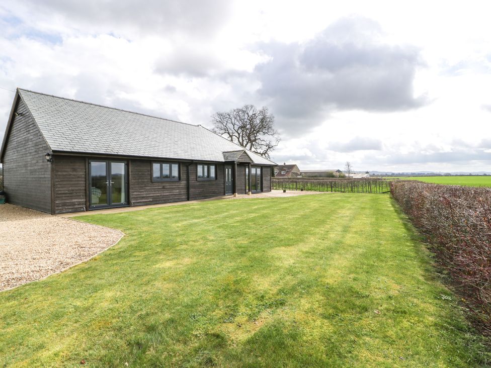 A single story house with dark wooden exterior surrounded by a lawn and hedges at Rectory Farm View Queen Camel near Yeovil