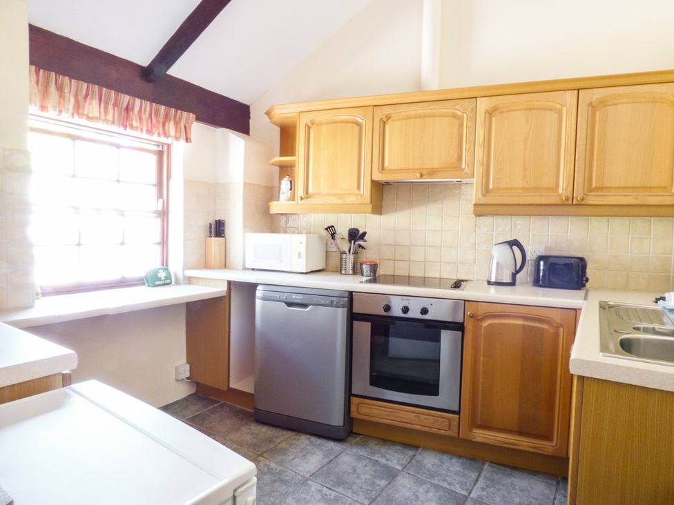 A kitchen with wooden cabinets stainless steel appliances microwave kettle and toaster at Parlour Cottage in Marazion