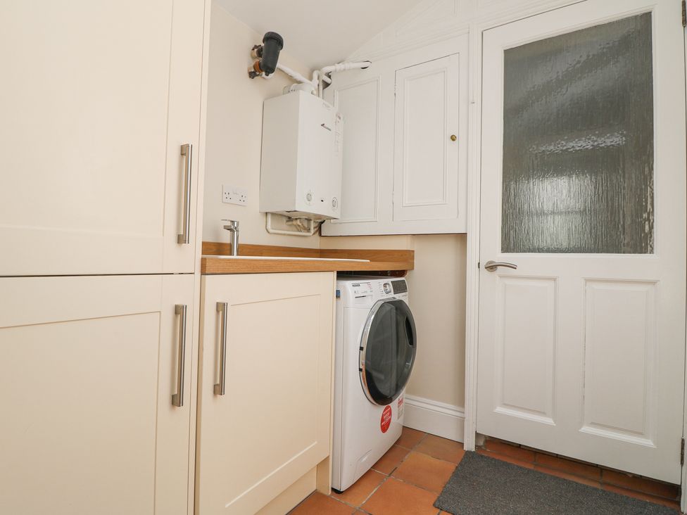 A laundry room with washing machine cabinets countertop boiler and a door at Rose Villa in Newlyn