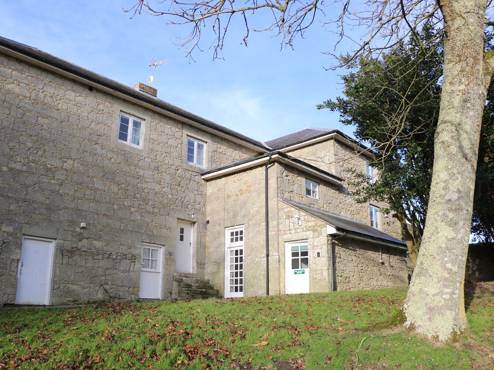 Stone building with white doors and windows on a grassy area with a tree at The Coach House in Wroxall