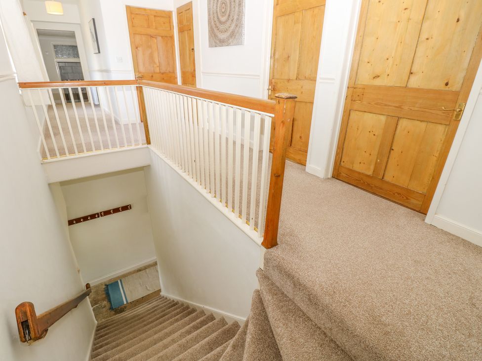 A carpeted hallway with wooden doors and a staircase with a wooden handrail at The Coach House in Wroxall