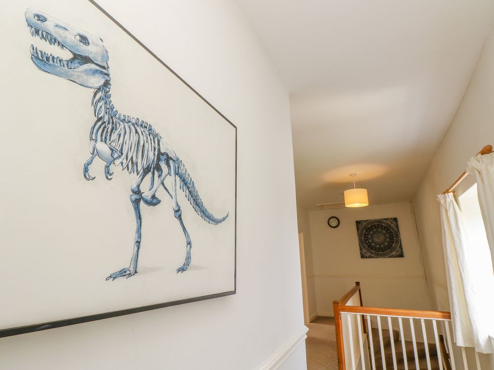 A hallway with a dinosaur skeleton painting on the wall a clock and circular artwork at The Coach House in Wroxall