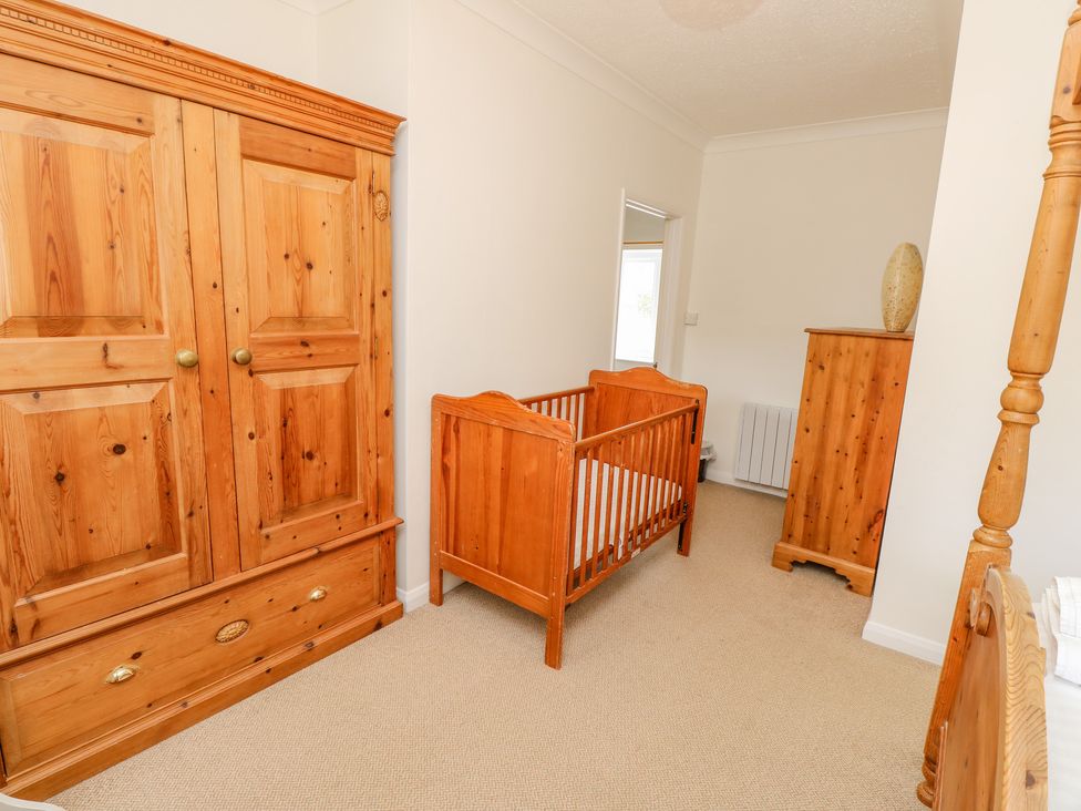 A bedroom with wooden crib wardrobe dresser and bedframe at The Coach House in Wroxall