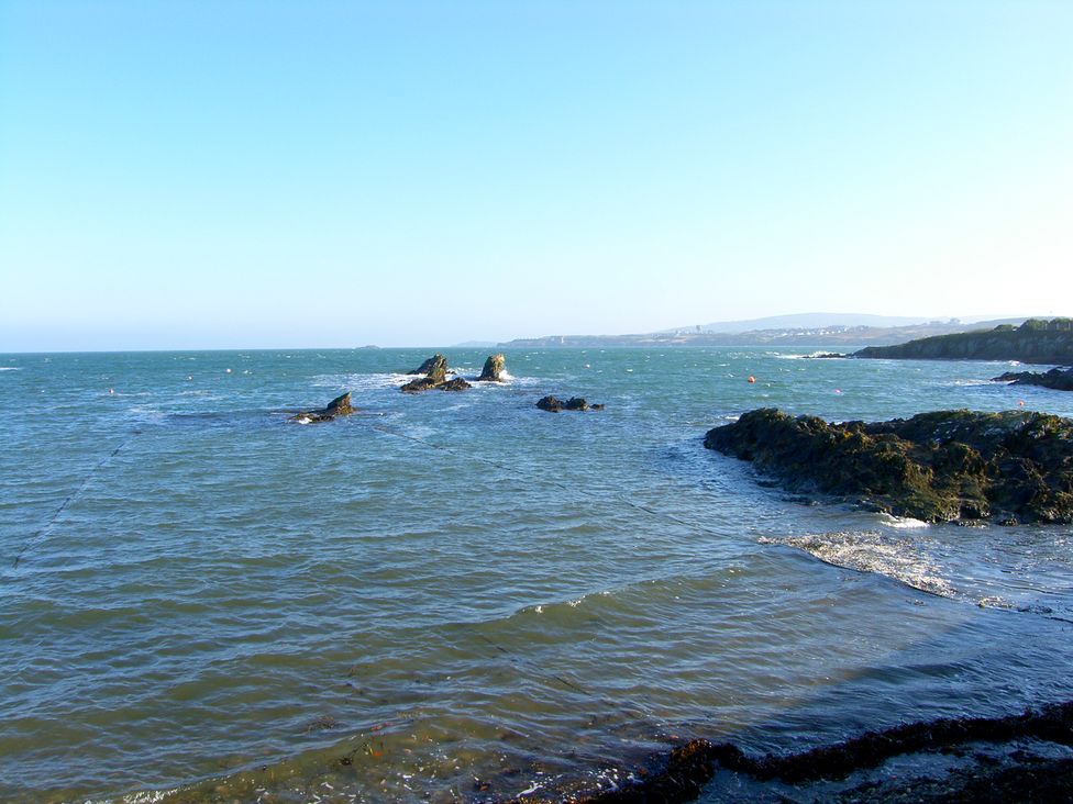 A rocky coastline with waves and distant hills at Bay Lodge in Bull Bay