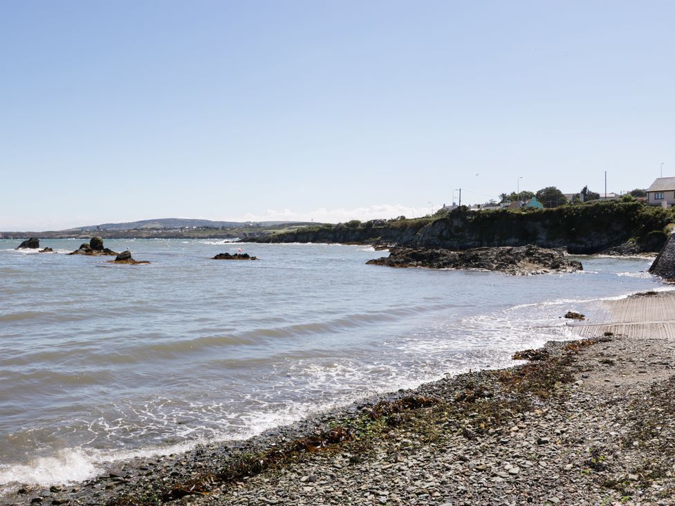 A rocky shoreline with waves and houses on a cliff in Bull Bay